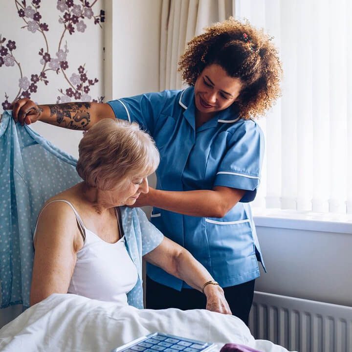 A nurse is helping an elderly woman in bed.