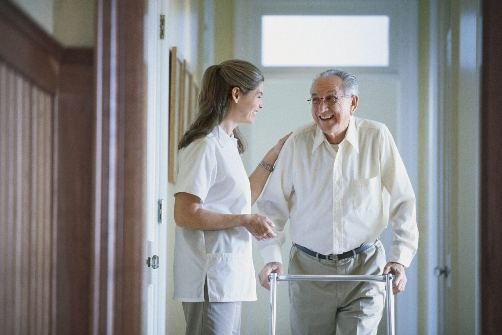 A woman and an old man walking in a hallway.