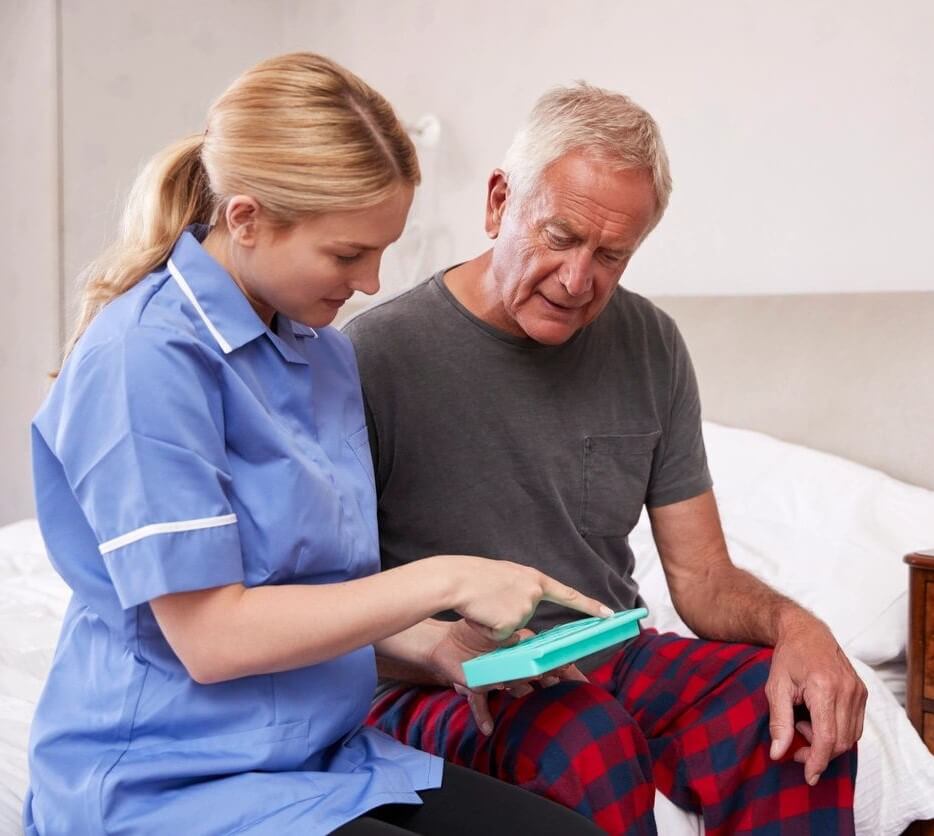 A nurse showing an elderly man something on his tablet.